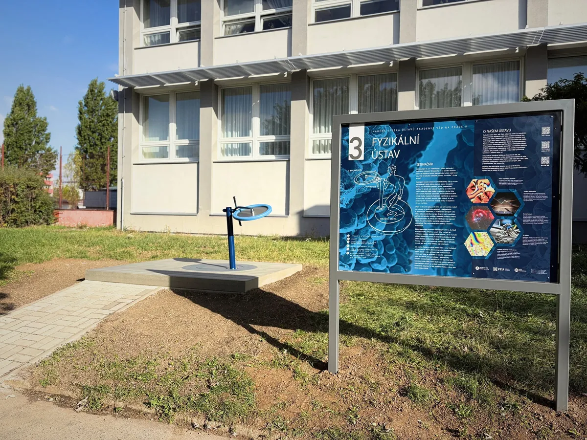 The flywheel on a wooden platform in front of the Institute of Physics building, next to the information panel of stop 3