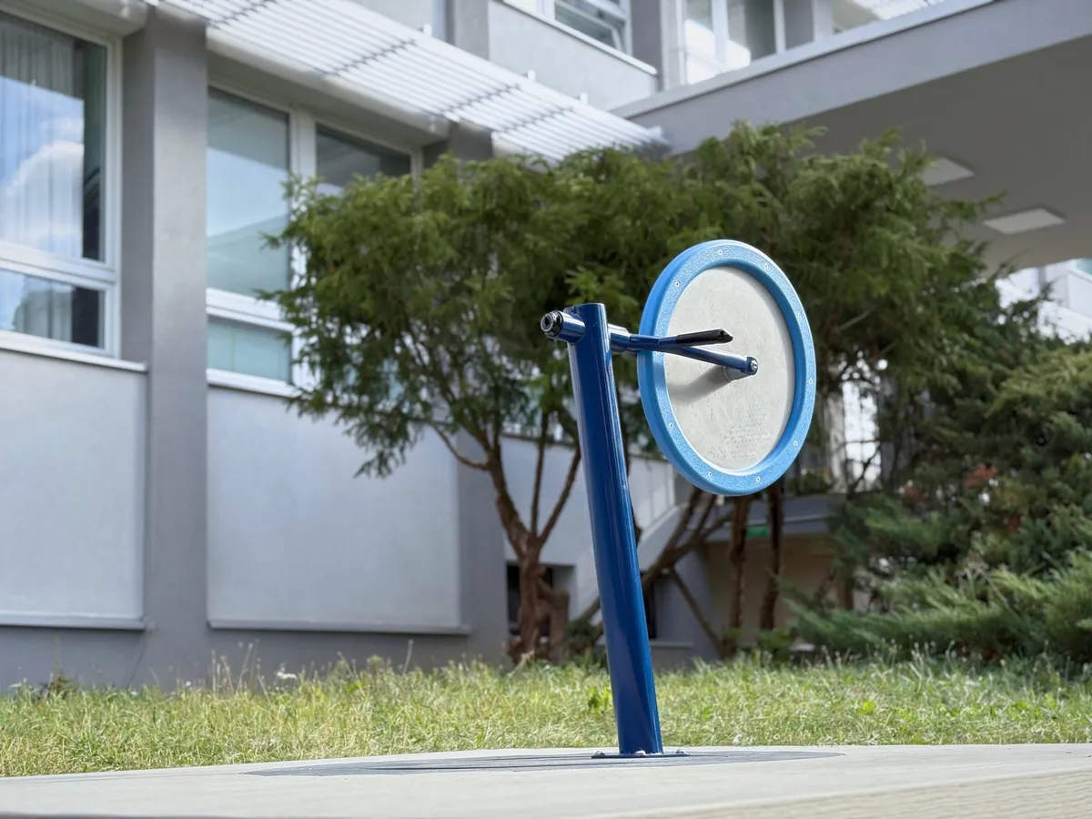 Close-up of the flywheel: a blue post with a rotating disc rimmed in light blue